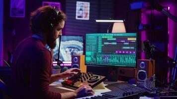 Artist improving the sound quality of audio recordings in home studio, handling mixing console and controls. Producer uses his creative vision to manipulate sounds, audio equipment. Camera B. video