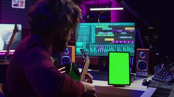 suono ingegnere pratiche giocando acustico chitarra utilizzando apprendimento App lezione su Telefono attraverso schermo verde isolato Schermo. giovane musicista apprendimento per giocare strumento con in linea Lezioni. telecamera b. video