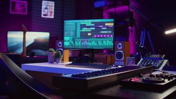 Empty studio at home equipped with mixing soundboard panel and other musical instruments, music industry recording. Modern space with electronic controls and daw software on pc. Camera B. video