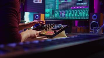 erfaren audio ingenjör användningar blandning styrelse till skapa ny låt i inspelning Hem studio. posta produktion Utrustning och verktyg på dator, fungerar digital audio arbetsstation programvara. kamera b. video