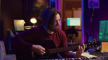 joven hombre compositor de canciones jugando guitarra y creando música utilizando igualada programa. músico grabación canción en hogar estudio, ingeniero mezcla y dominar popular rock pistas cámara una. video