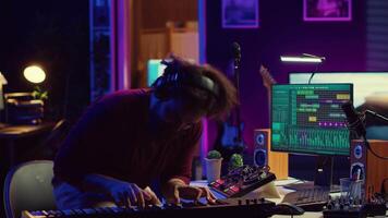 Energetic confident artist playing electronic piano in home studio, recording midi controller synthesizer notes to add audio effects. Cheerful sound engineer having fun with keyboard. Camera A. video