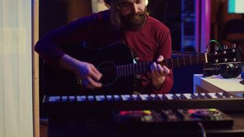 artiste travail avec choucas Logiciel à le sien Accueil studio à record Nouveau la musique sur mélange console et table d'harmonie, l'audio ingénierie. musicien en jouant chanson sur guitare et ajustement volume. caméra un. video