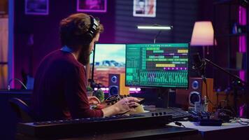 Music engineer operates recording equipment in home studio, working with mixing consoles and digital audio workstations to create sound effects on soundtracks. Production techniques. Camera A. video