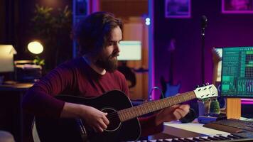 musicien en essayant à régler le du son de le sien guitare dans Accueil studio, ajustement boutons avant en jouant airs et enregistrement sur choucas logiciel. Avancée mélange et Maîtriser techniques. caméra un. video