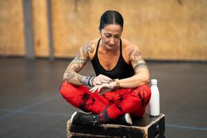 Strong mature sportswoman using smart watch sitting in the gym photo