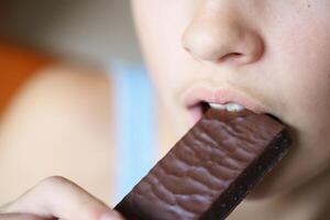 Crop anonymous teenage girl biting nutritious protein bar photo