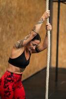 Tired sportive woman climbing a rope in a gym photo