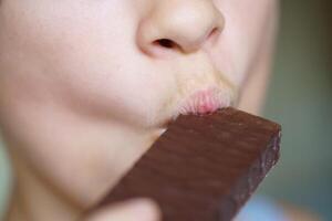 cosecha irreconocible niña comiendo delicioso chocolate proteína bar foto