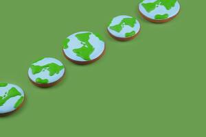 Earth Day concept. Cookies in shape of Earth on green backdrop. photo