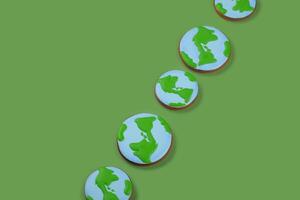 Earth Day concept. Cookies in shape of Earth on green backdrop. Copy space. photo