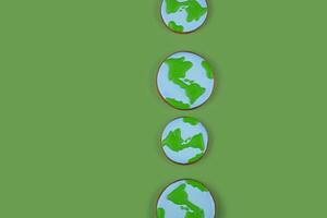 Earth Day concept. Cookies in shape of Earth on green backdrop. Background with copyspace. photo