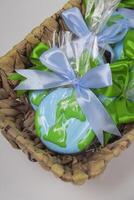 A basket filled with cookies in shape of Earth on green backdrop. Earth Day concept. photo