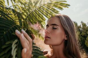 Beauty portrait of happy woman closeup. Young girl smelling Chinese acacia pink blossoming flowers. Portrait of young woman in blooming spring, summer garden. Romantic vibe. Female and nature photo