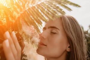 Beauty portrait of happy woman closeup. Young girl smelling Chinese acacia pink blossoming flowers. Portrait of young woman in blooming spring, summer garden. Romantic vibe. Female and nature photo