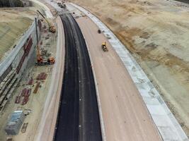 Mountain road constraction. Workers reinforce the slope over the new road. Road construction in progress on slope nature canyon. Infrastructure development and logistics. Aerial drone shot photo