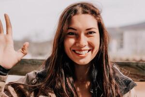 Happy young smiling woman with freckles outdoors portrait. Soft sunny colors. Outdoor close-up portrait of a young brunette woman and looking to the camera, posing against autumn nature background photo