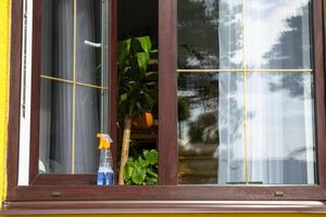 A window cleaning spray, a rag and a mop stand on the window sill of an open window outside for spring general cleaning photo