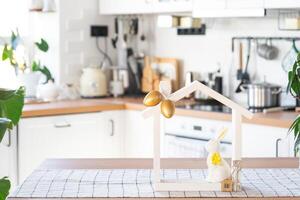 Key and tiny house of cozy home with Easter decor with rabbit and eggs on table of kitchen. Building, design, project, moving to new house, mortgage, insurance, rent and purchase real estate photo