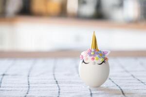 Easter craft - decorates an egg in the form of a unicorn with rhinestones, horn, flowers in the interior of a house photo