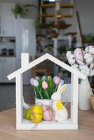 Tiny house of cozy home with Easter decor with rabbit and eggs on table of kitchen. Building, design, project, moving to new house, mortgage, insurance, rent and purchase real estate photo