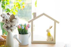 Tiny house of cozy home with Easter decor with rabbit and eggs on table of kitchen. Building, design, project, moving to new house, mortgage, insurance, rent and purchase real estate photo