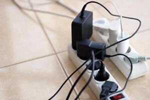 Overloaded power boards. Power strips with different electrical plugs on white floor photo