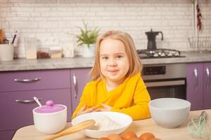 retrato de pequeño niña de Tres años viejo, cocina, tarta, incursionando, divertido. mira dentro cámara. foto