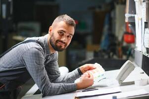 Print house worker controlling printing process quality and checking colors with magnifying glass photo