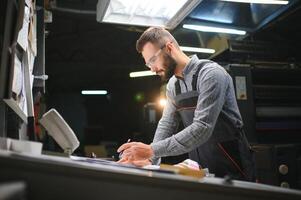 Graphic engineer or worker checking imprint quality in modern print shop photo