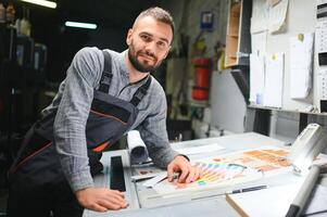 Print house worker controlling printing process quality and checking colors with magnifying glass photo