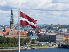 panorama de riga ciudad con un grande letón bandera en primer plano foto