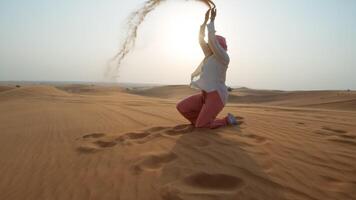 donna giocando con il sabbia nel il difficile sole di arabo deserto video