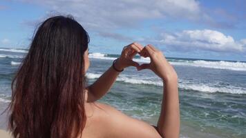 contento niña a un playa a puesta de sol. en forma de dedo corazón forma. verano sueño. felicidad de libertad en un playa a puesta de sol. video