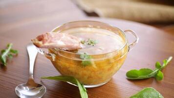 cooked pea soup with ribs smoked in a plate on a wooden table video