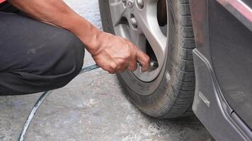 man driver hand inflating tires of vehicle, removing tire valve nitrogen cap for checking air pressure and filling air on car wheel at gas station. video