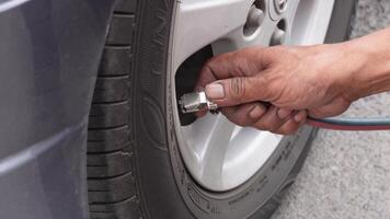 man driver hand inflating tires of vehicle, removing tire valve nitrogen cap for checking air pressure and filling air on car wheel at gas station. video