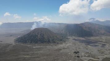 aéreo ver de activo volcán con cráter en profundidad. marrón suciedad alrededor. nubes de fumar en volcán, montar bromo, Indonesia video