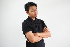 young Asian man in casual black polo t shirt with arm crossed tired of a repetitive task looking at camera studio shot isolated on white background photo