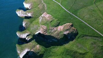 aereo Visualizza di un' aspro costa con scogliere e un' strada in esecuzione parallelo per il mare. video