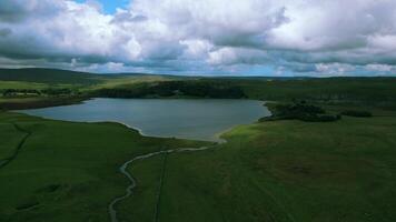 Aerial view of a serene lake with a winding path under a dramatic cloudy sky. video