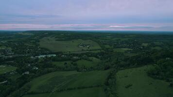 aérien vue de une luxuriant campagne paysage à crépuscule avec des champs et des arbres en dessous de une de mauvaise humeur ciel. video