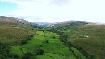 Aerial view of lush green valleys with rolling hills and a country road, under a cloudy sky. video