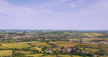 Aerial view of a lush countryside with patchwork fields and a small town under a clear blue sky. video