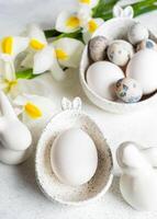 Easter natural colors eggs in bowls with bunny ears, bunnies, white Iris flowers on white close up. photo