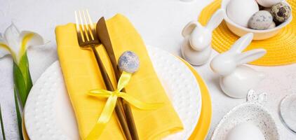 Easter table decorations. Golden cutlery, plates, small bunnies, natural colors eggs, white Iris. photo