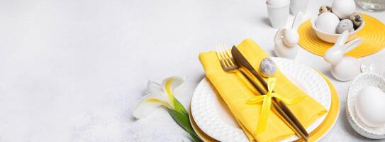 Easter banner Beautiful tableware, golden cutlery, ceramic bunnies, eggs, white Iris flower on white photo