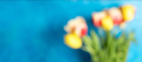 Defocused image with colorful tulips bouquet on bright blue background. Copy space. photo