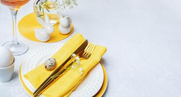 Table setting for Easter holiday in white with yellow colors. Banner. Close up. Copy space. photo