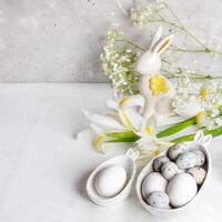 Easter. Natural eggs in figured bowls with bunny ears, ceramic bunny, white Iris, Gypsophila flowers photo